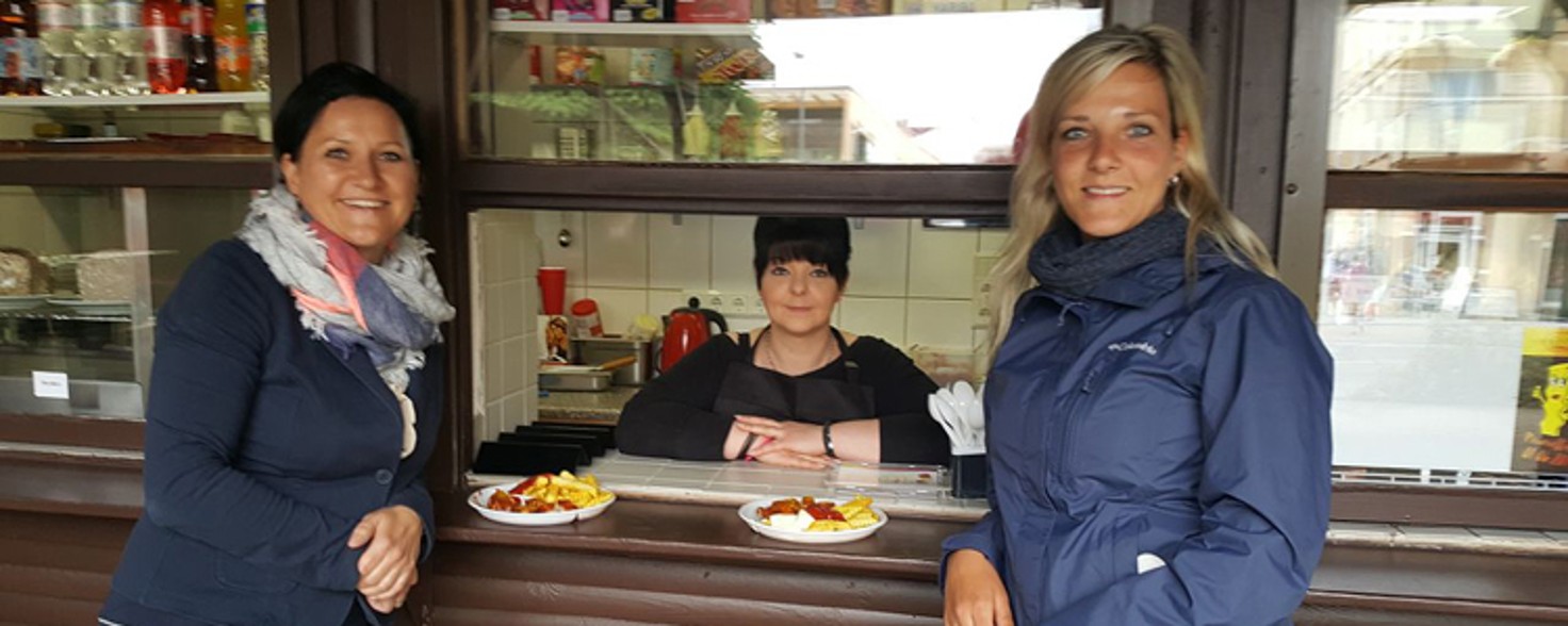 Zwei Frauen stehen an einem Imbiss, zwei Portionen Pommes stehen auf dem Tresen