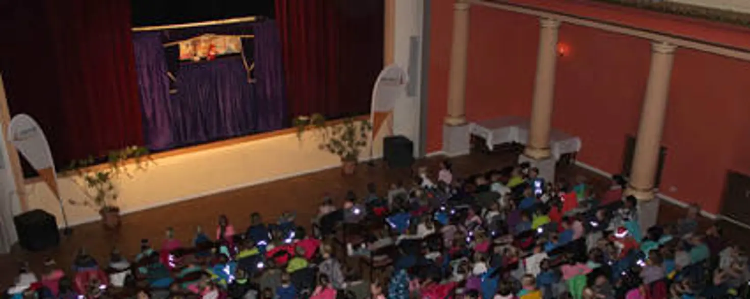 Ein Saal voll Publikum, auf der Bühne ein Puppentheater