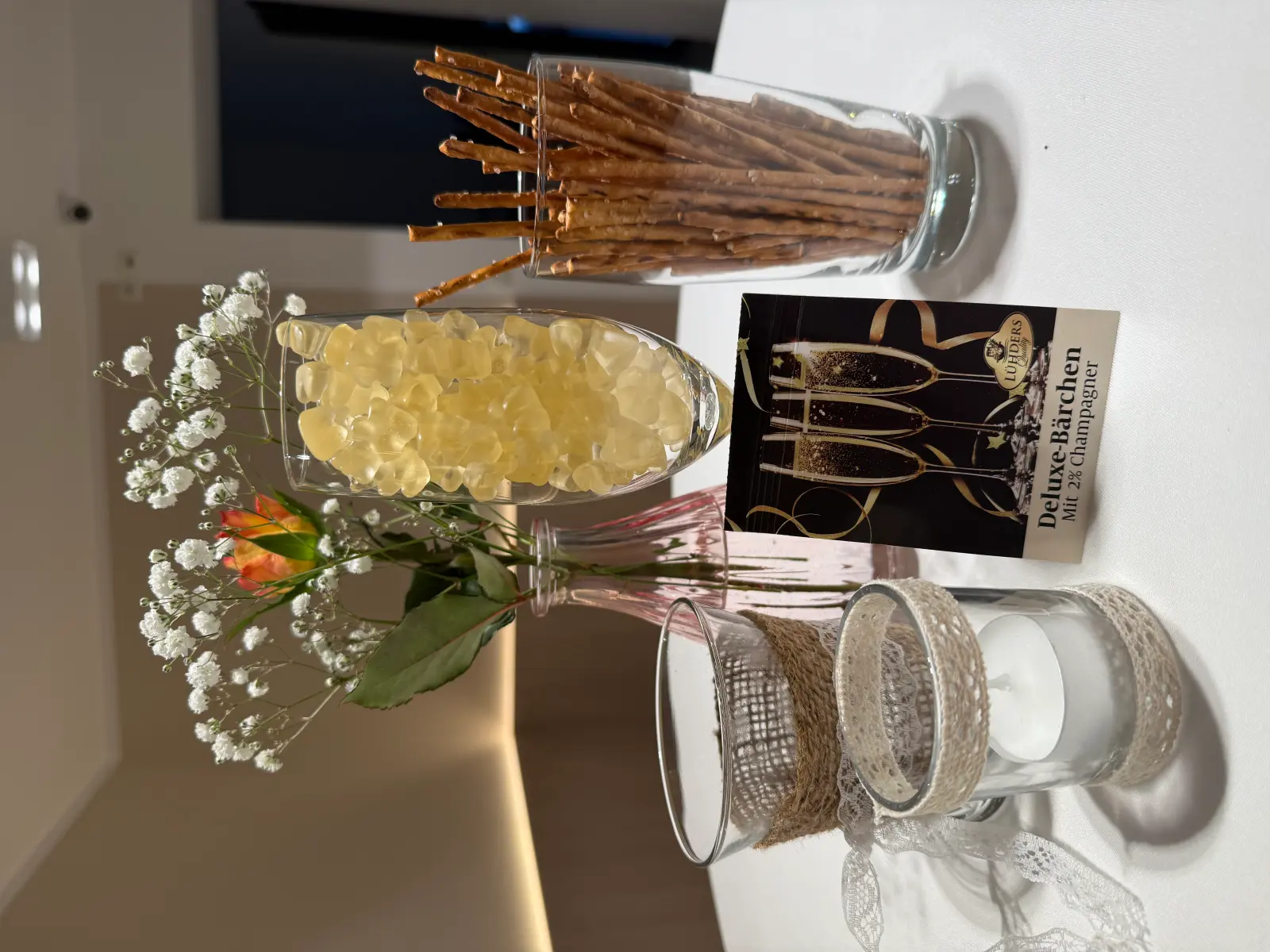 Gedeckter Tisch mit Blumen, Salzstangen, Deko und einer Karte mit der Aufschrift 