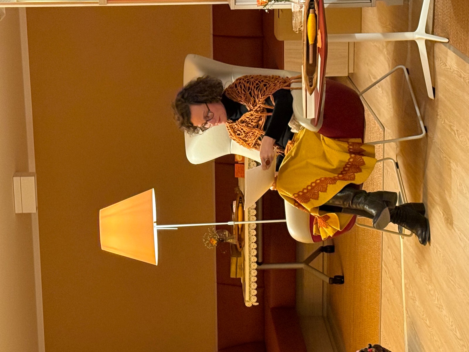 Frau sitz in einem weißen Sessel und liest ein aus einem weißen Blatt