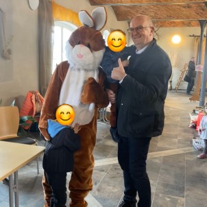 Ministerpräsident steht mit zwei Kindern neben einem Mensch in Hasenkostüm
