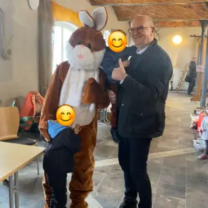 Ministerpräsident steht mit zwei Kindern neben einem Mensch in Hasenkostüm