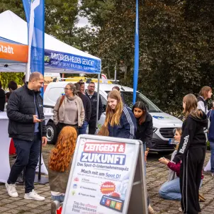 Ein blaues Pavillion der Marke Rewe präsentiert sich mit den Worte Zeitgeist und Zukunft. Davor stehen sechs junge Mädchen.