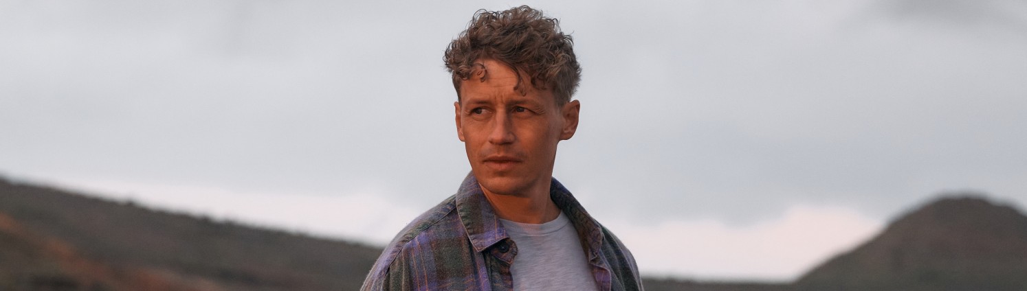 Der Sänger Tim Bendzko steht in der Naturlandschaft