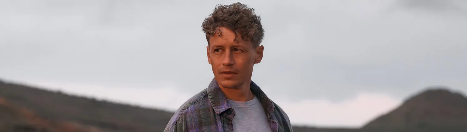 Der Sänger Tim Bendzko steht in der Naturlandschaft