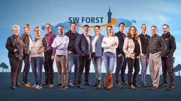 14 Menschen nebeneinander in Business-Outfits oder leger gekleidet lächeln in die Kamera