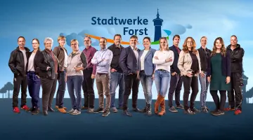 14 Menschen nebeneinander in Business-Outfits oder leger gekleidet lächeln in die Kamera